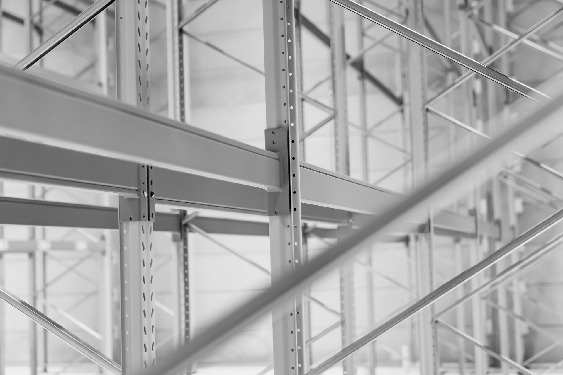 Empty industrial warehouse shelves with metal beams and bright windows in black and white.