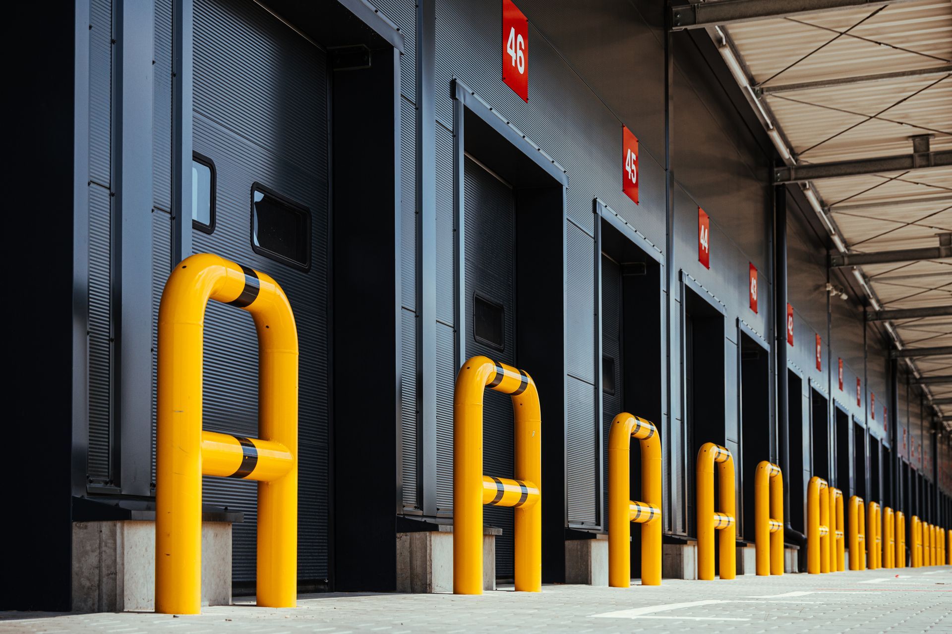 Loading dock doors with yellow safety rails along a warehouse exterior