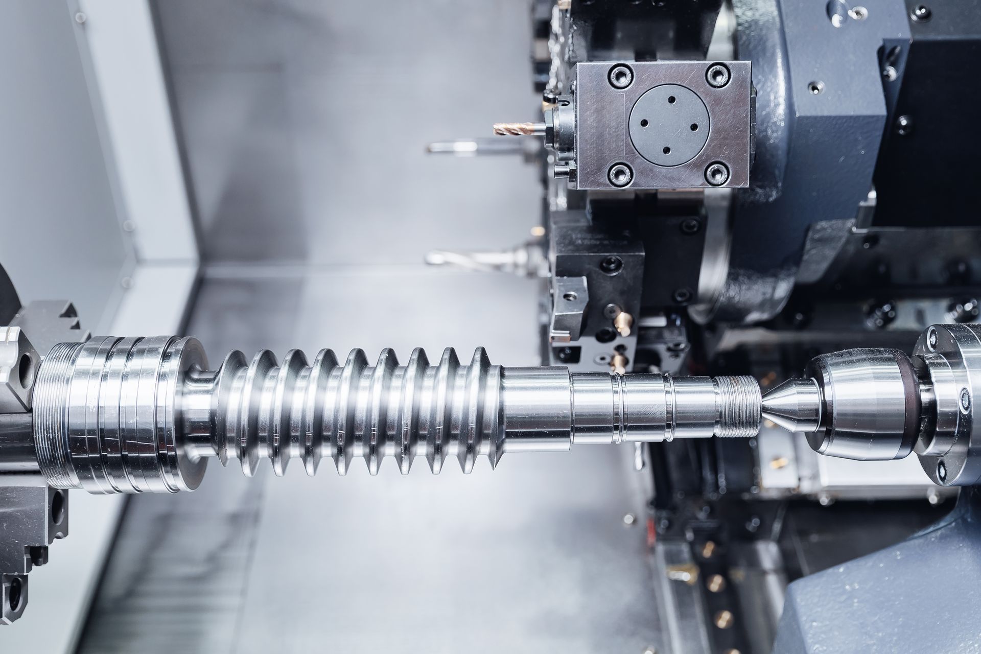 Industrial machine cutting a metal screw shaft on a CNC lathe