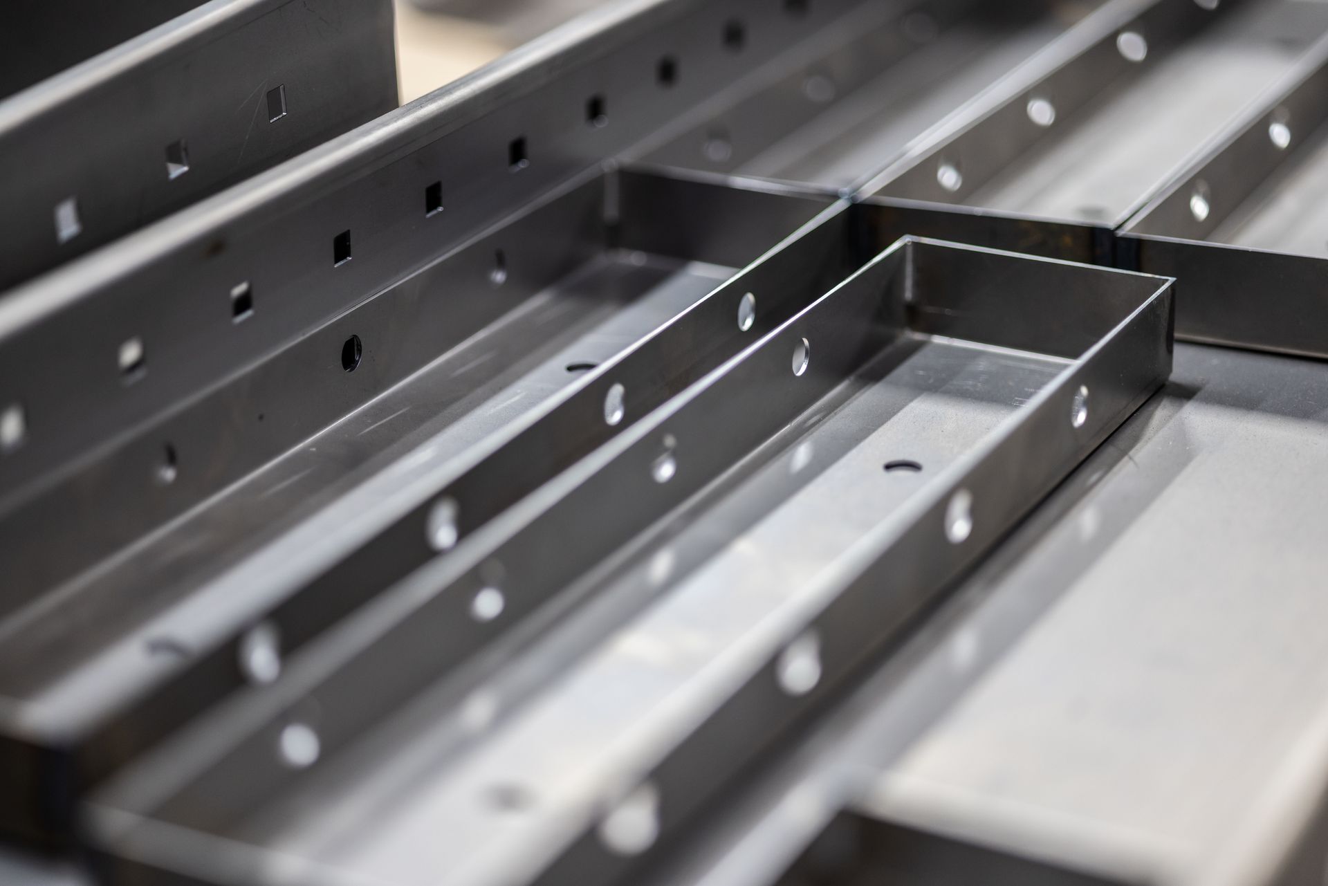 Metal shelves and brackets with perforated holes in a workshop or manufacturing setting