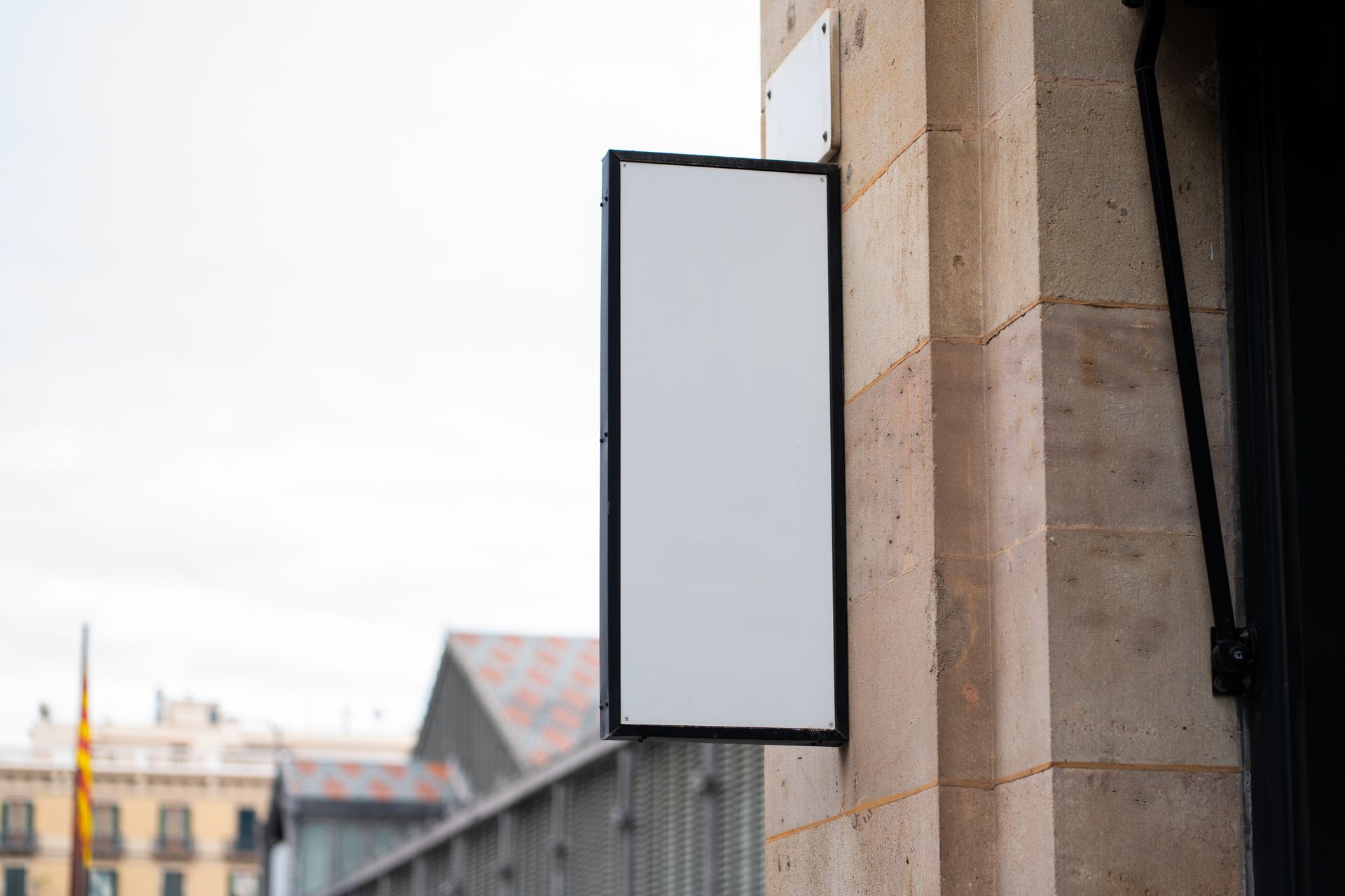 Blank rectangular sign mounted on a stone wall outside a building