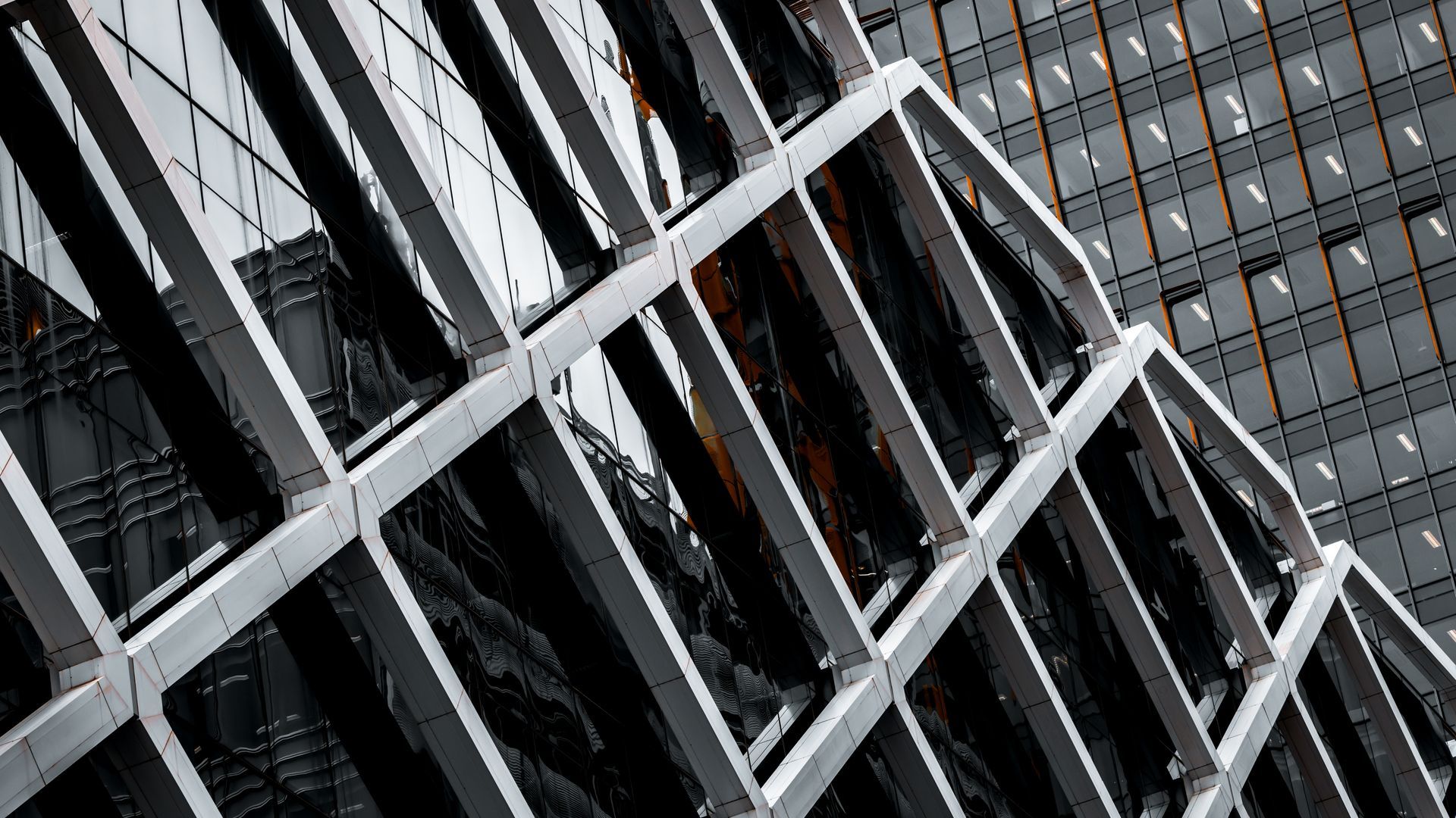 Abstract view of a modern glass building with diagonal white metal beams and dark window panels