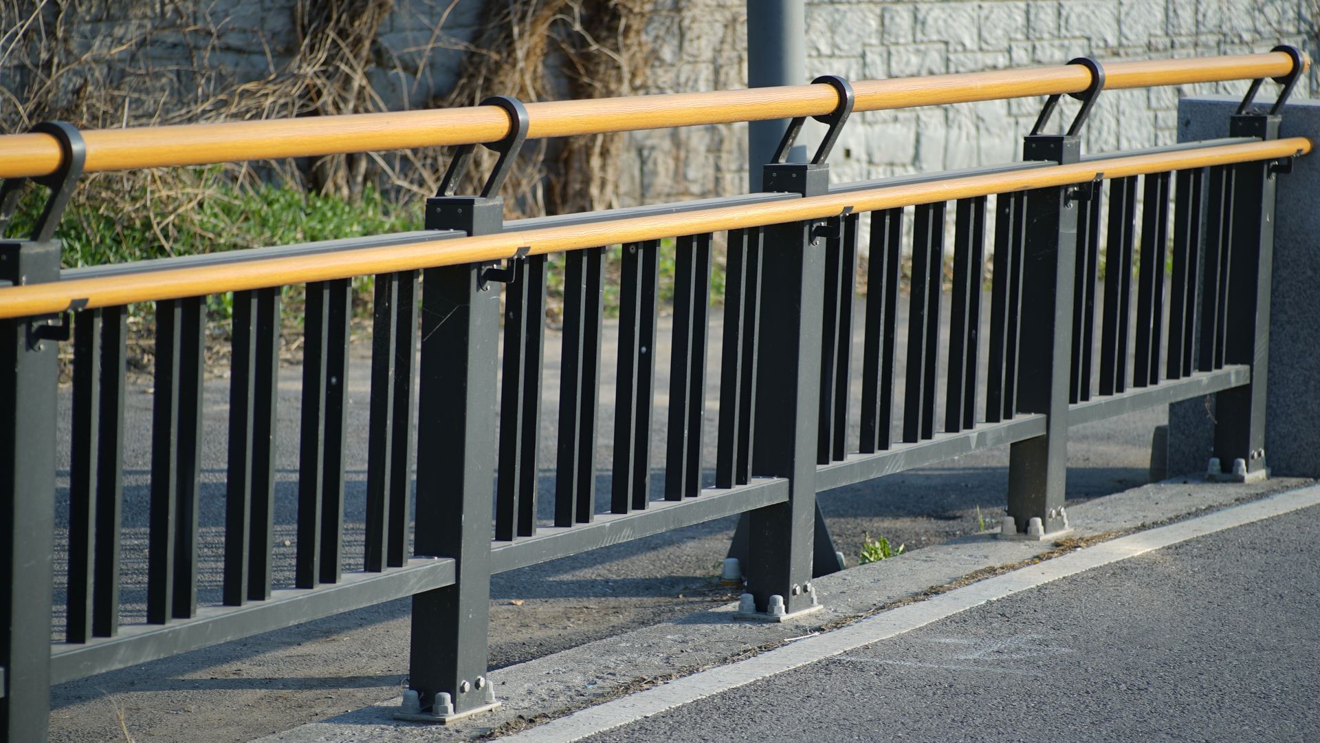 Black roadside guardrail with yellow top rail along a paved road