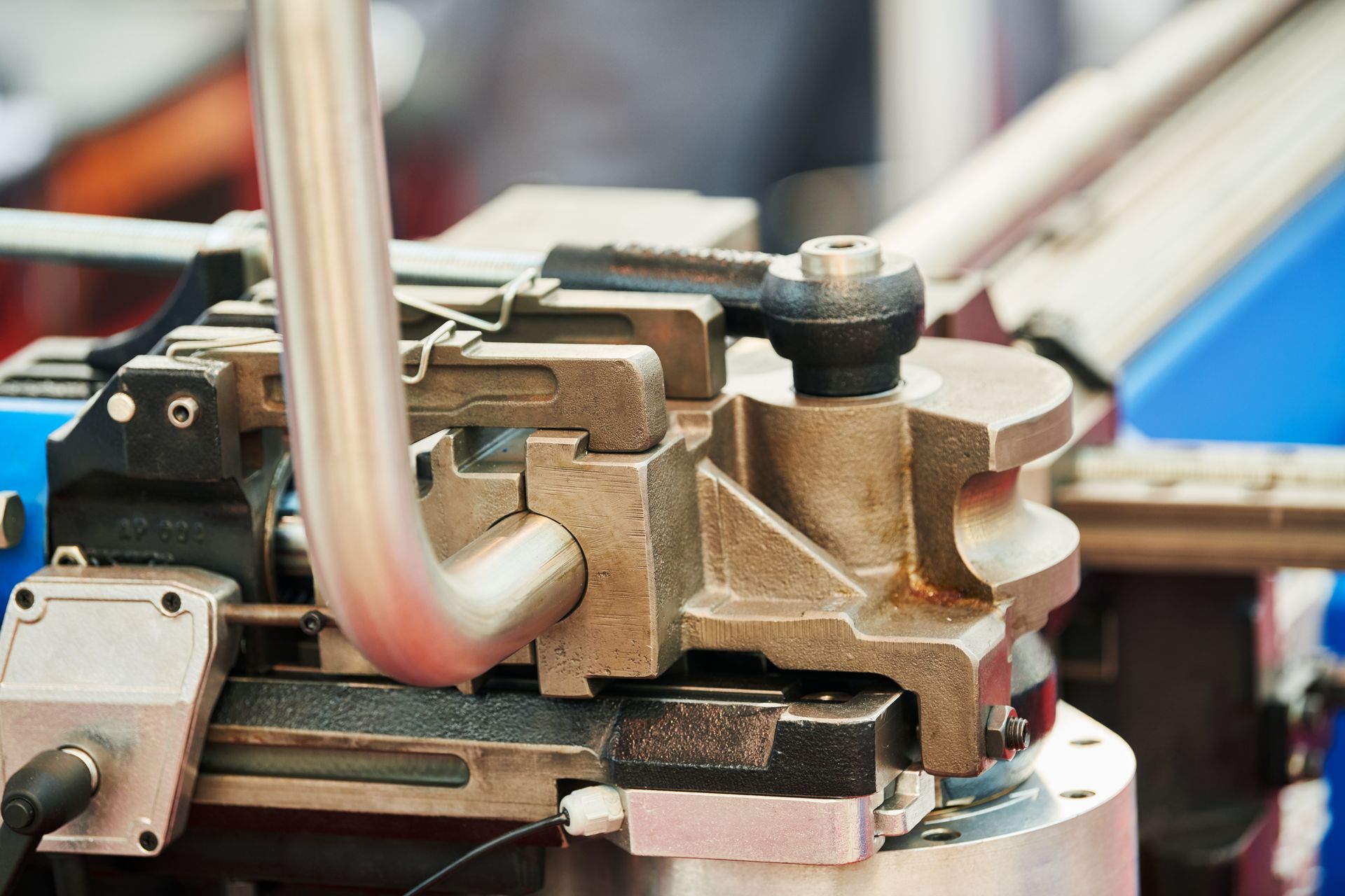 Close-up of a metal machine component with bolts, pipes, and brackets on an industrial assembly line