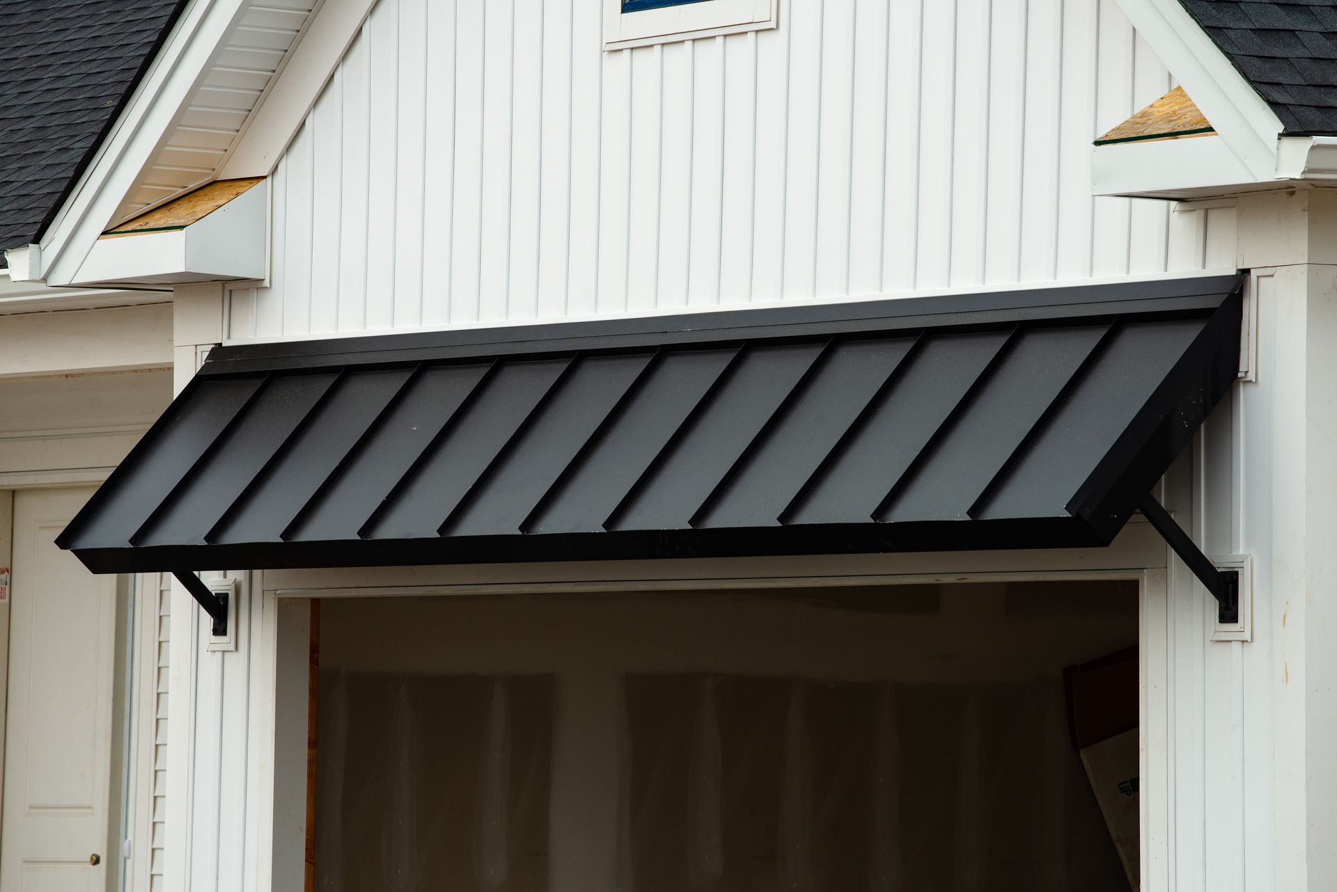 Black metal awning over a garage entrance on a white house