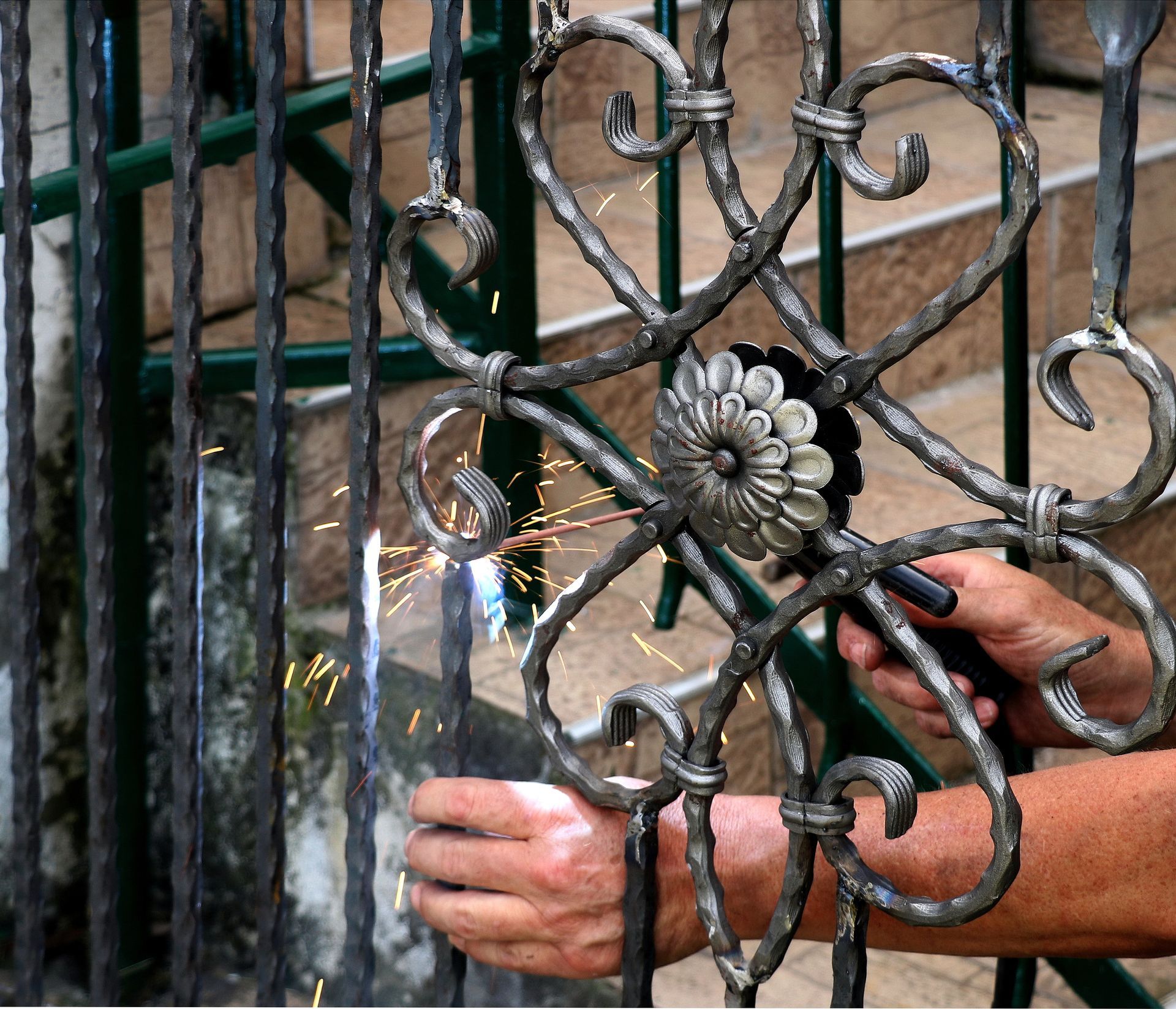 Hands fastening a decorative iron gate lock behind a transparent plastic sheet