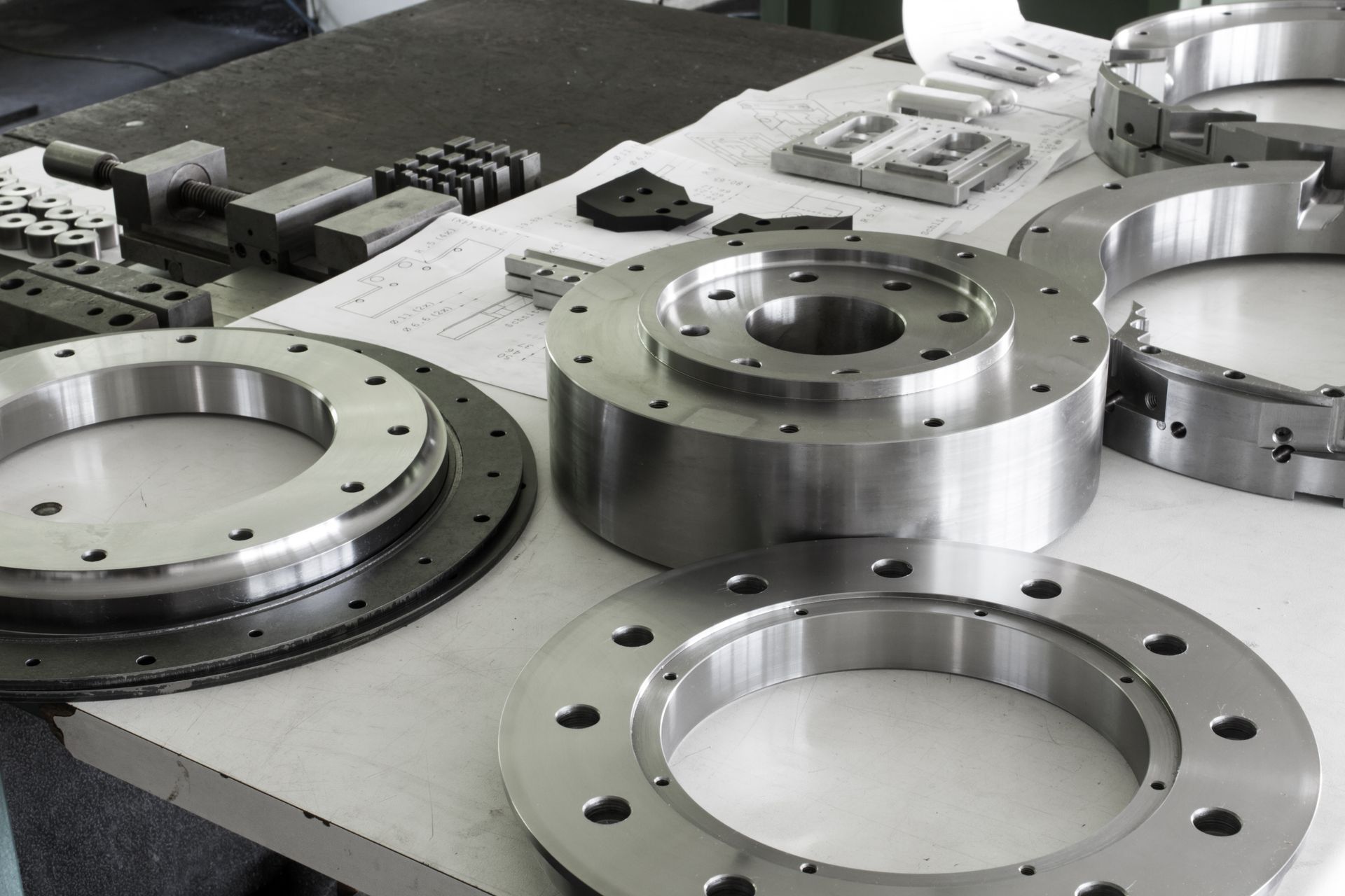 Metal flanges and machined parts arranged on a workbench in a factory setting