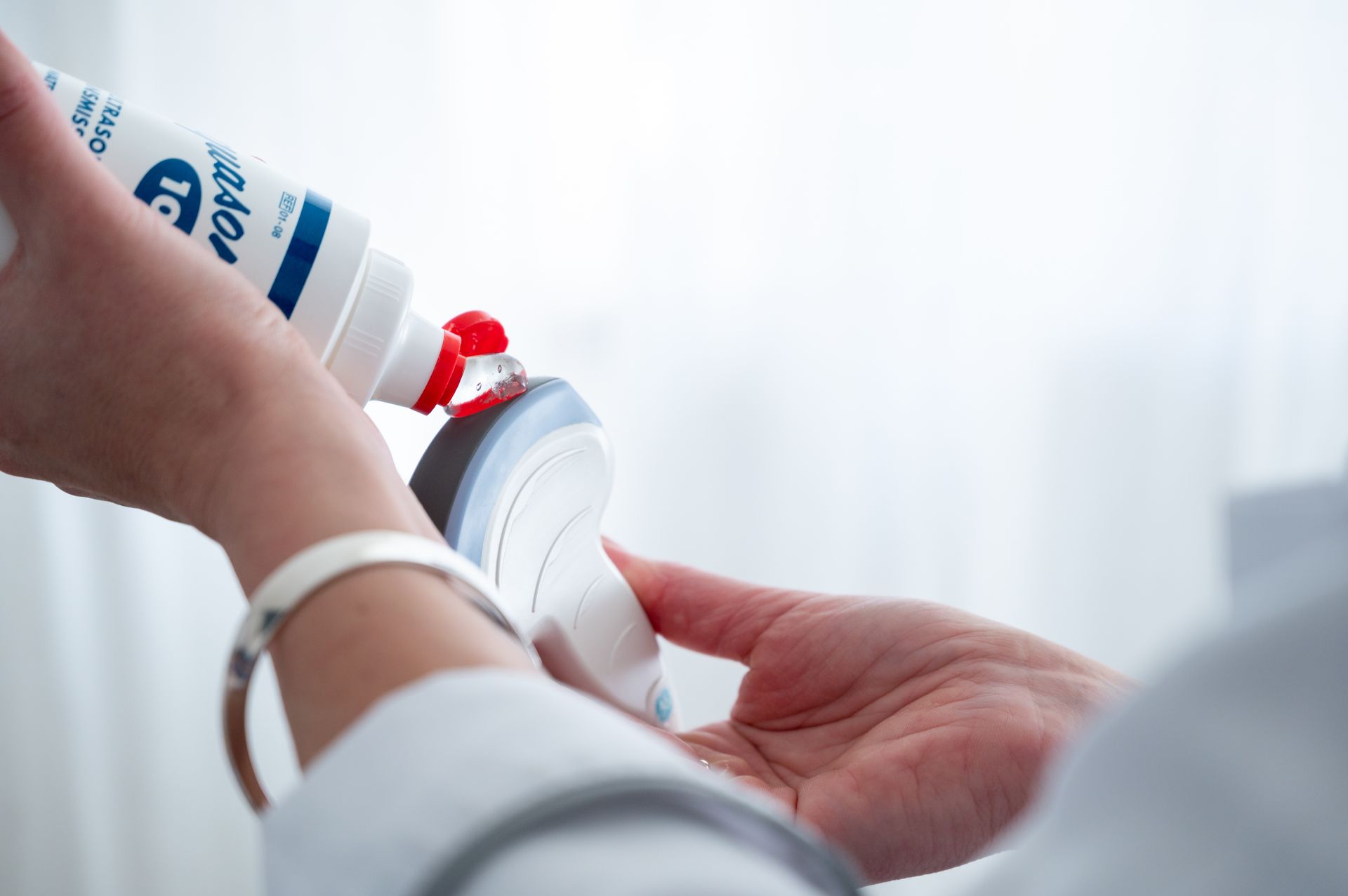 Eine Person hält eine Tube Ultraschallgel in der Hand und gibt es auf den am Handgelenk.