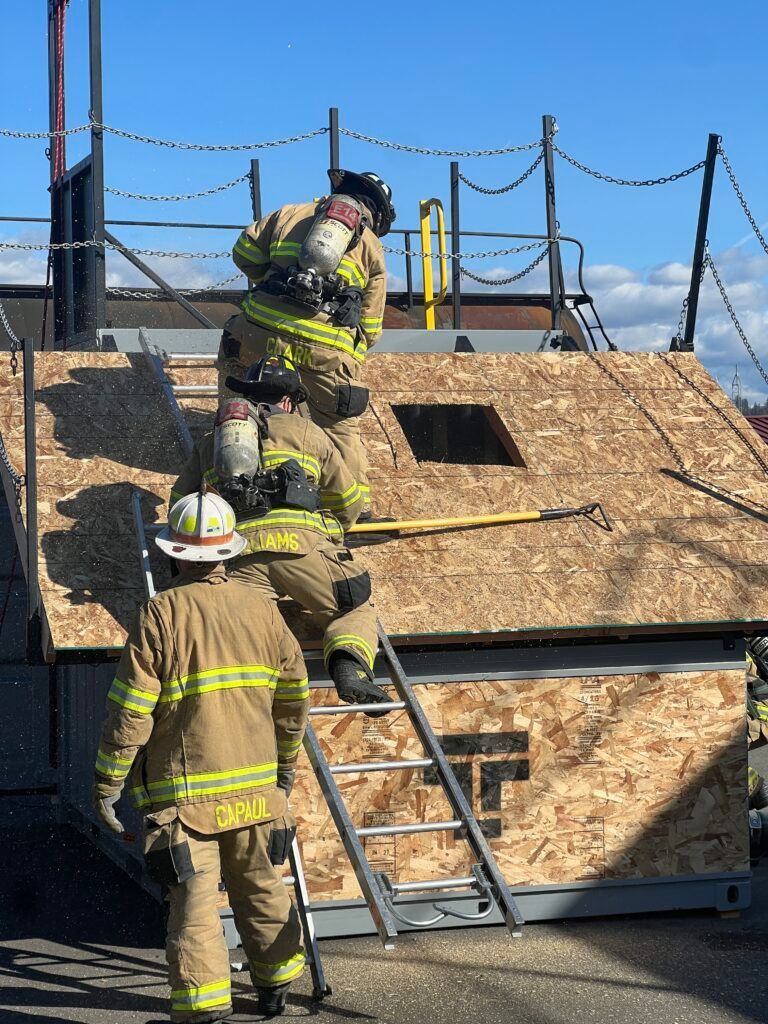 A group of firefighters are working on the roof of a building.