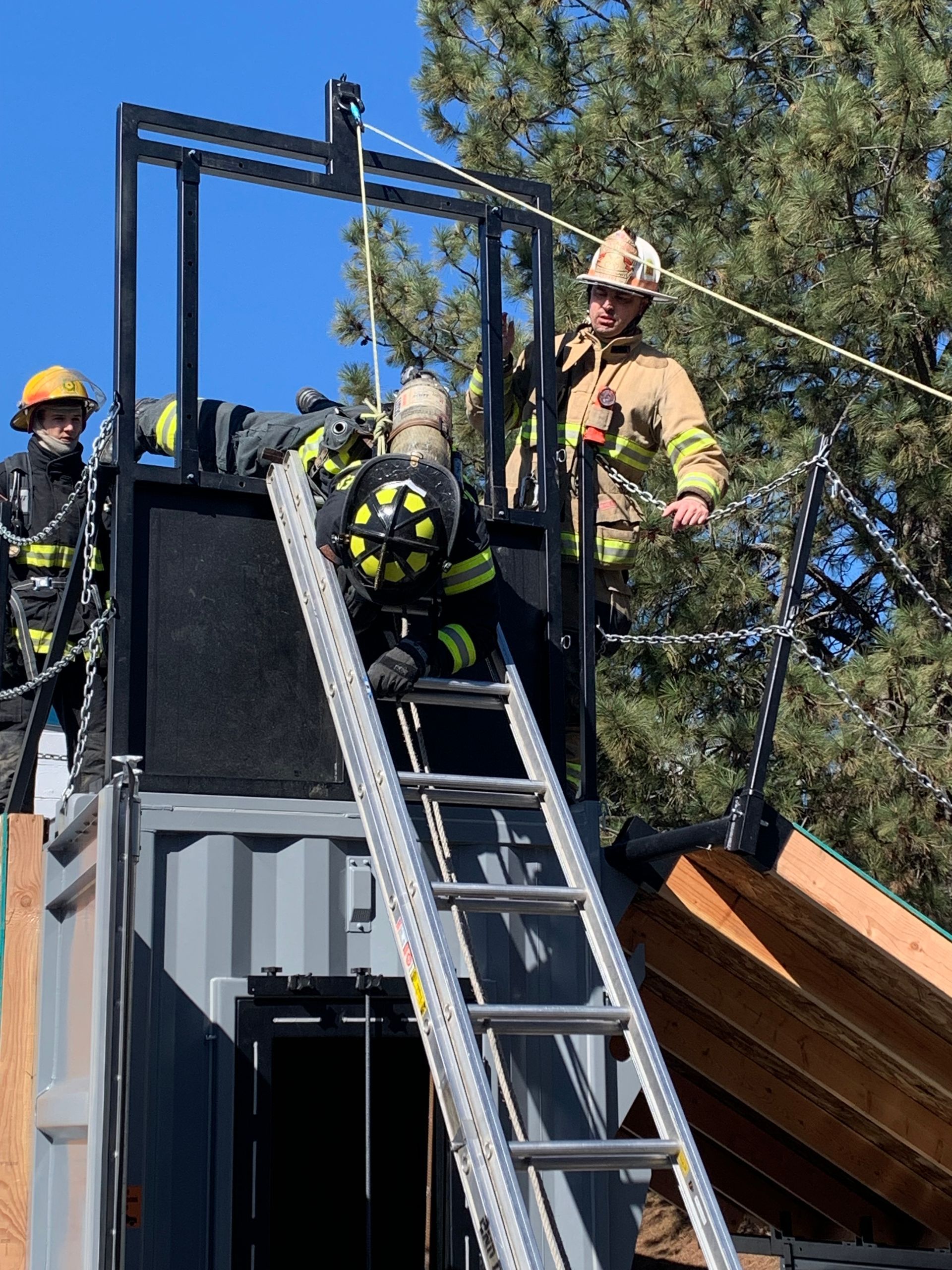 A group of firefighters are standing on top of a ladder.