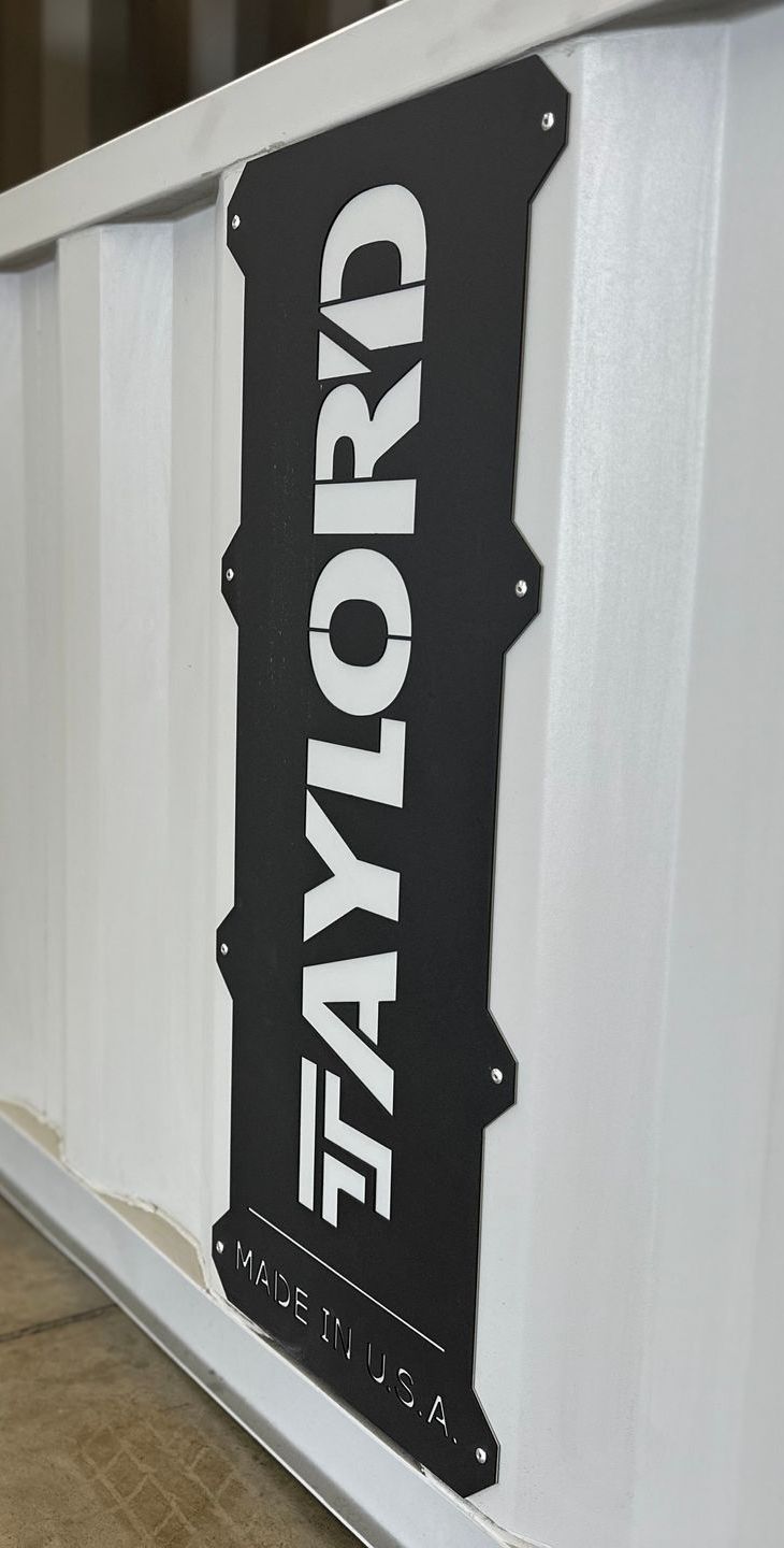 A black sign with the word taylor on it is hanging on a white wall.