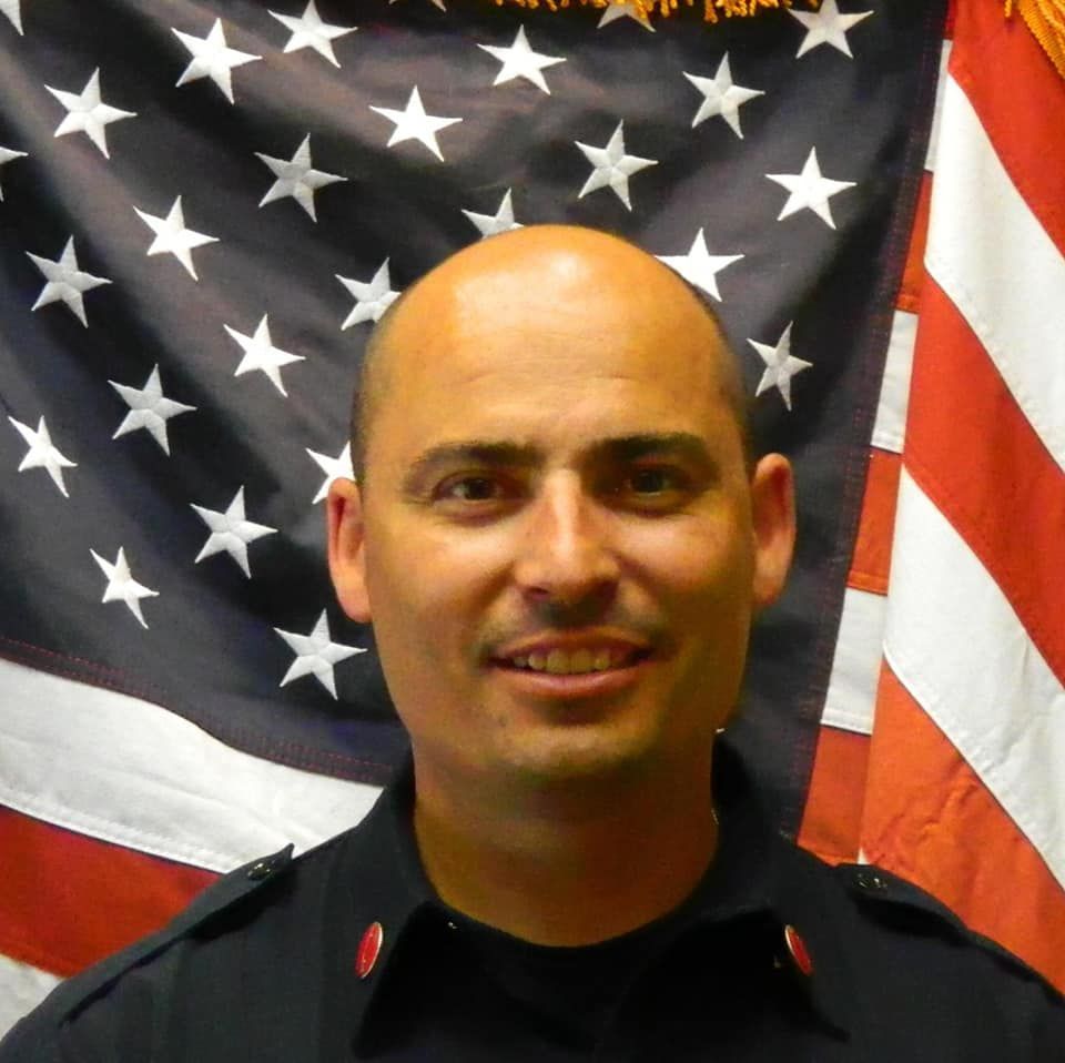 A man stands in front of an american flag