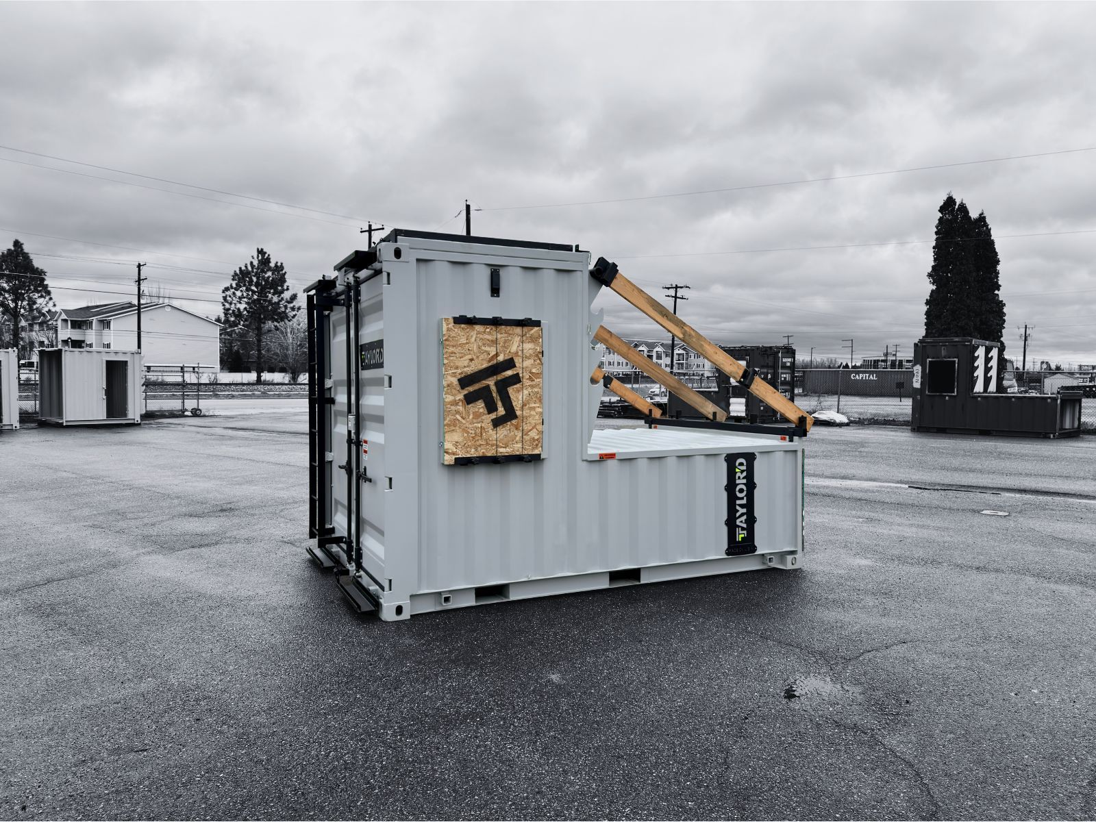 A white shipping container with a wooden sign and supports, outdoors on a cloudy day.