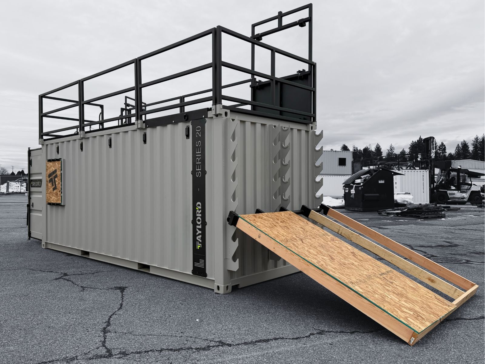 Black and white photo of a training structure built on a shipping container, with stairs and a ramp, outdoors.