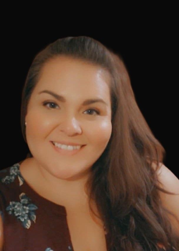 A woman with long brown hair is smiling for the camera.