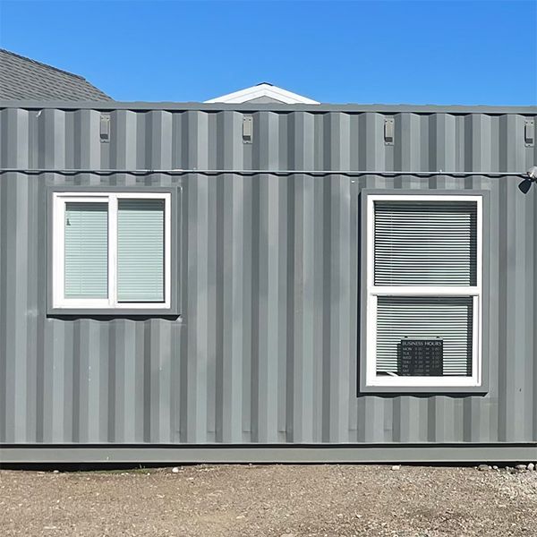 A gray shipping container with two windows on the side of it.