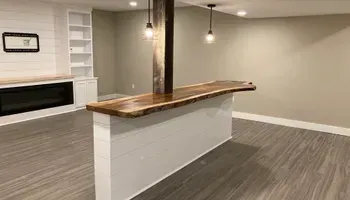 A basement with a wooden bar and a fireplace.