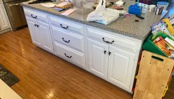 A kitchen with white cabinets and a wooden floor.