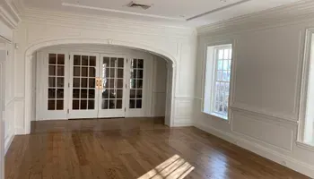 A large empty room with hardwood floors and white walls.