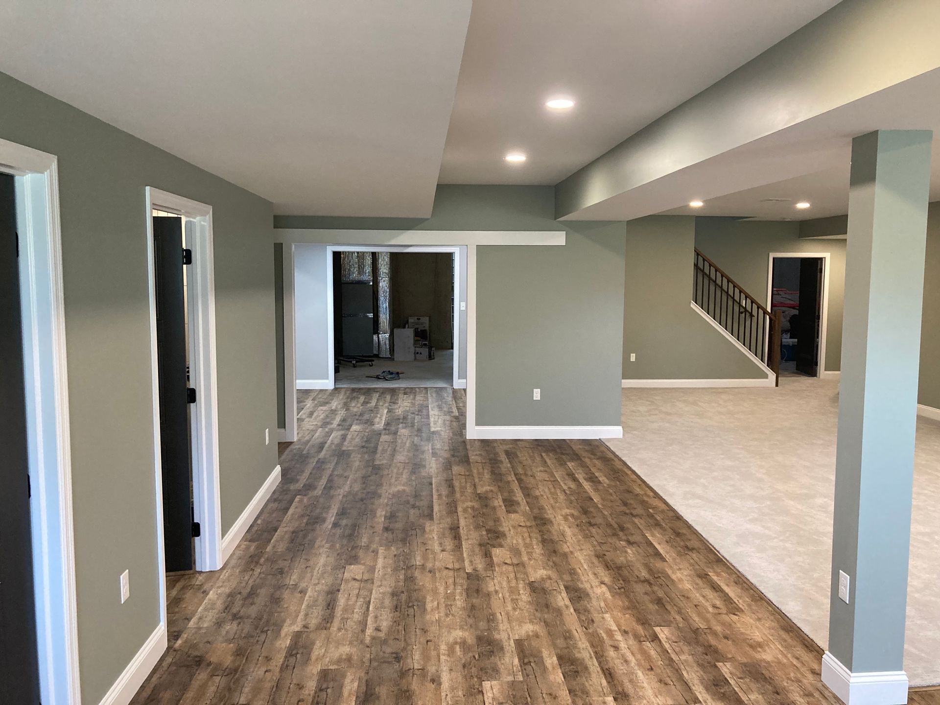 A large empty basement with hardwood floors and a staircase.