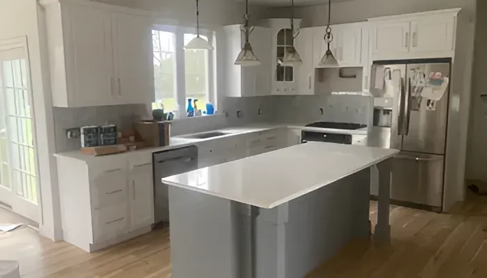 A kitchen with white cabinets , stainless steel appliances , and a large island.