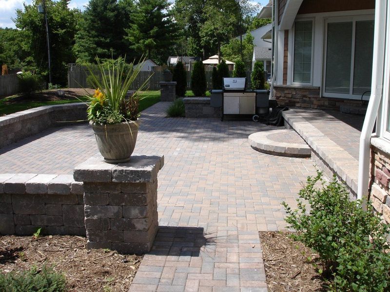 Brick patio with a large planter, grill, and low retaining walls.