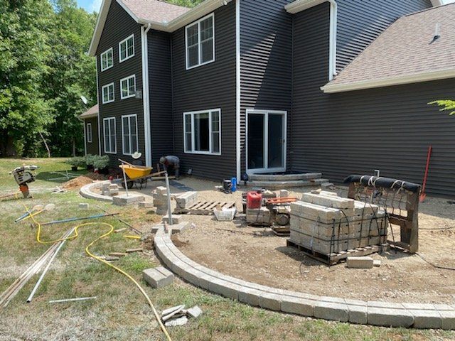Construction site with a house, patio blocks, and equipment.