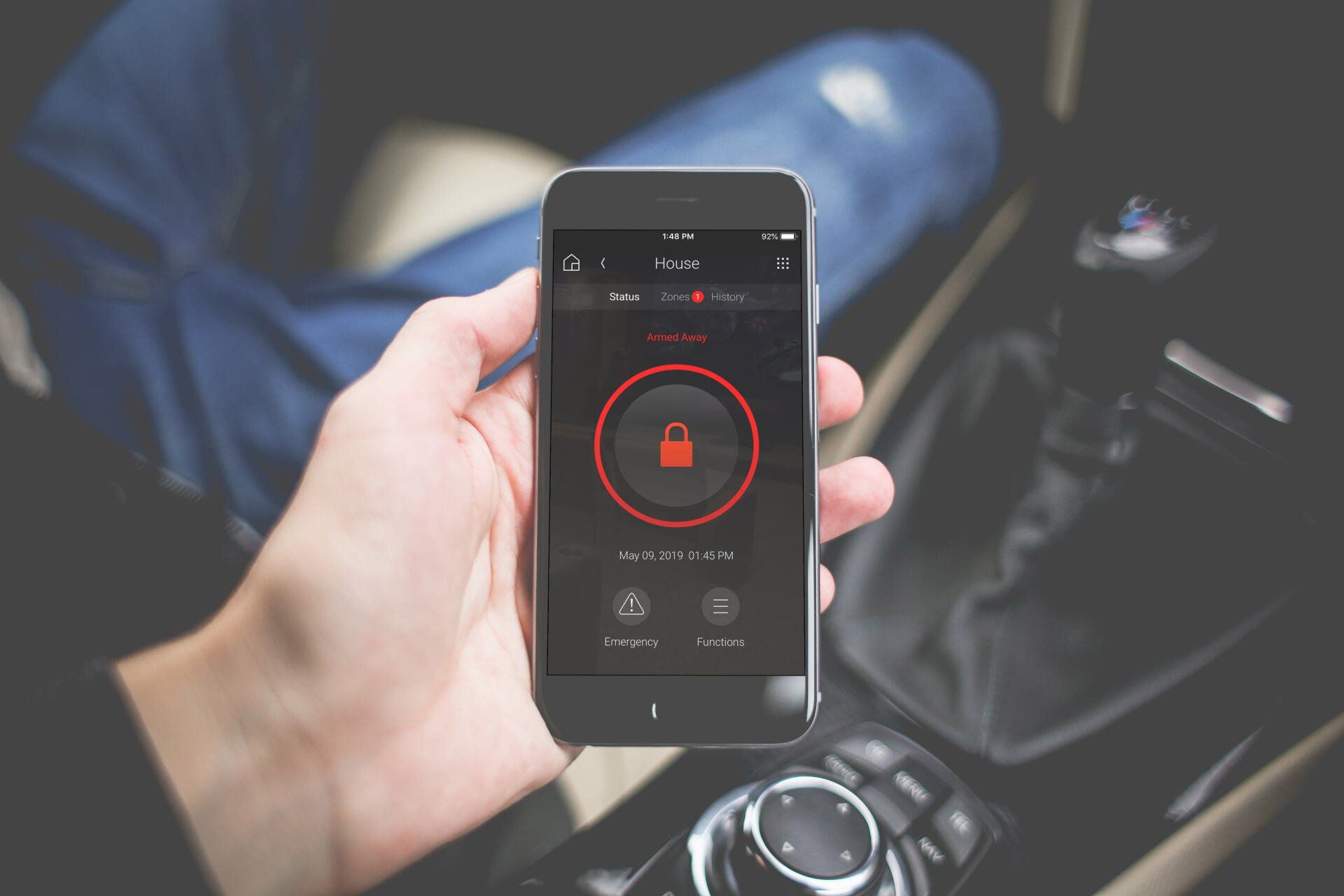 A person is holding a cell phone in their hand in a car.