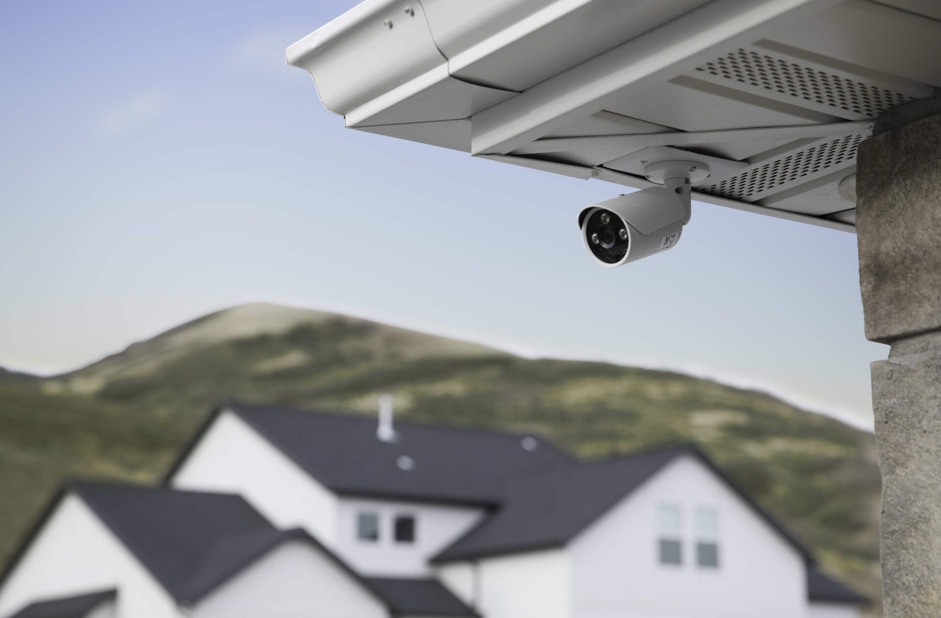 A security camera is mounted on the roof of a house