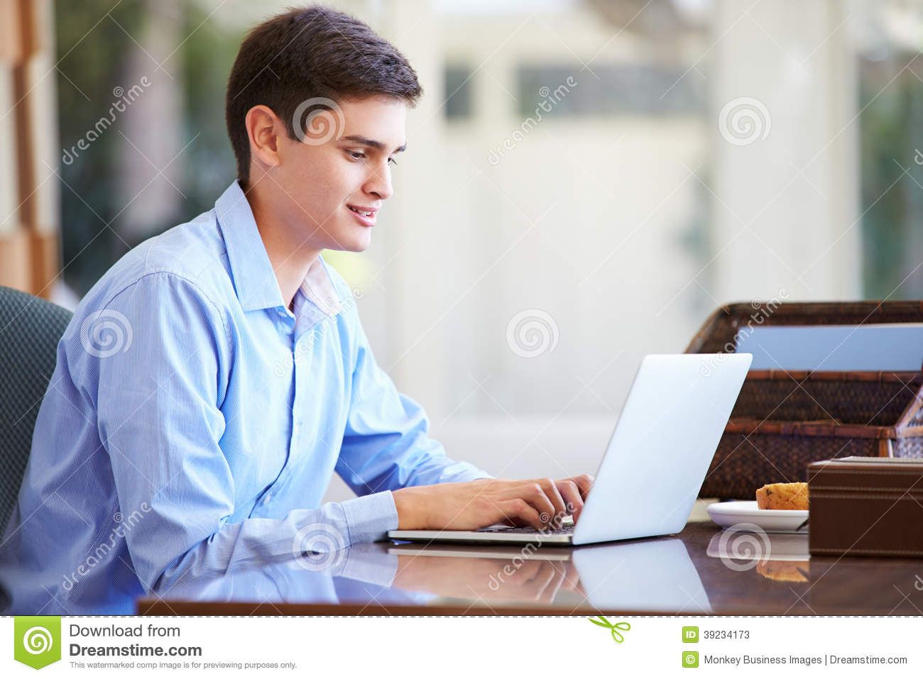 A man is sitting at a desk using a laptop computer.
