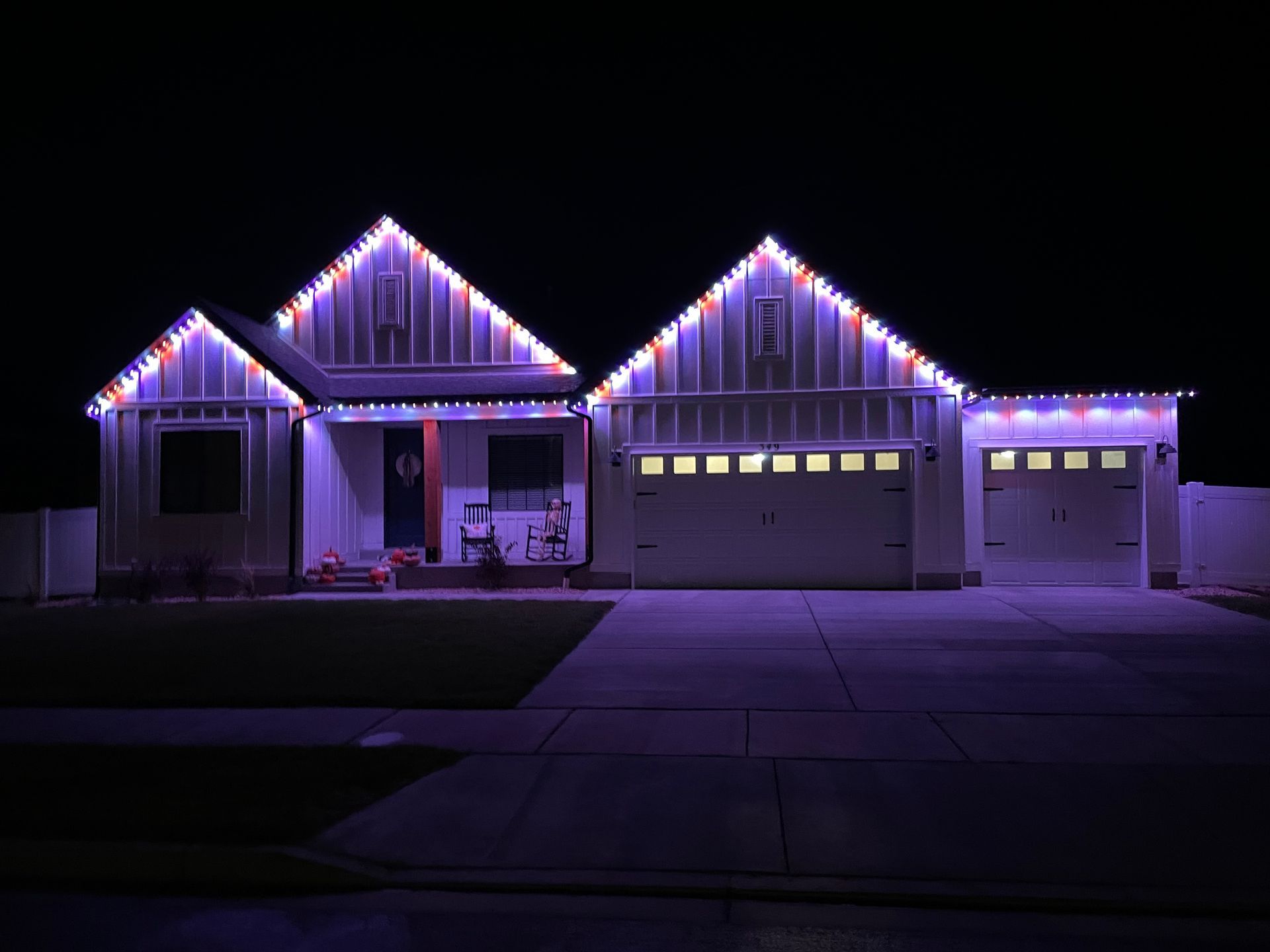A house with christmas lights on it is lit up at night.