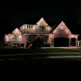 A log cabin is lit up at night with string lights hanging from the roof.