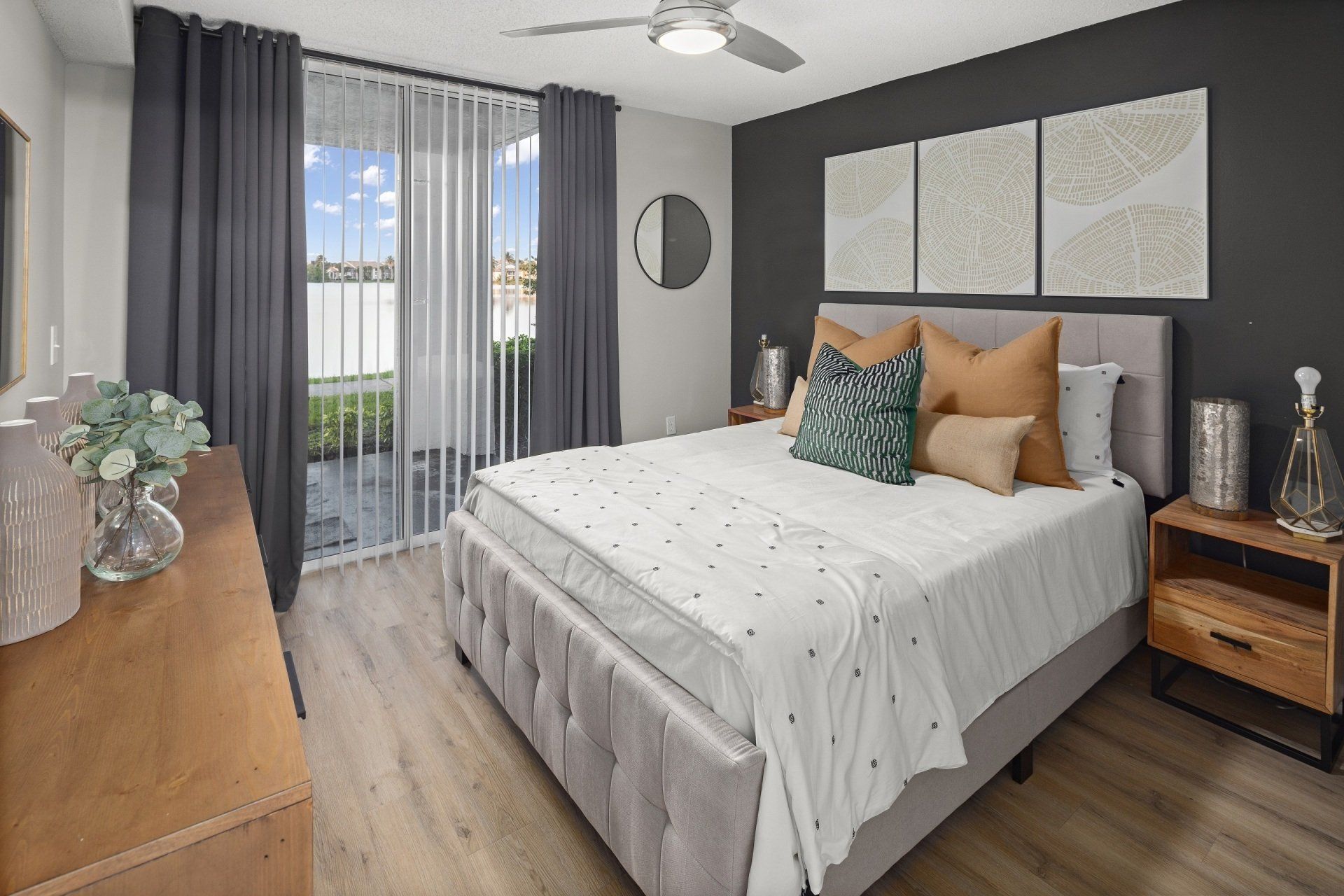 Bedroom with a gray bed, dark accent wall, and sliding door to a patio.