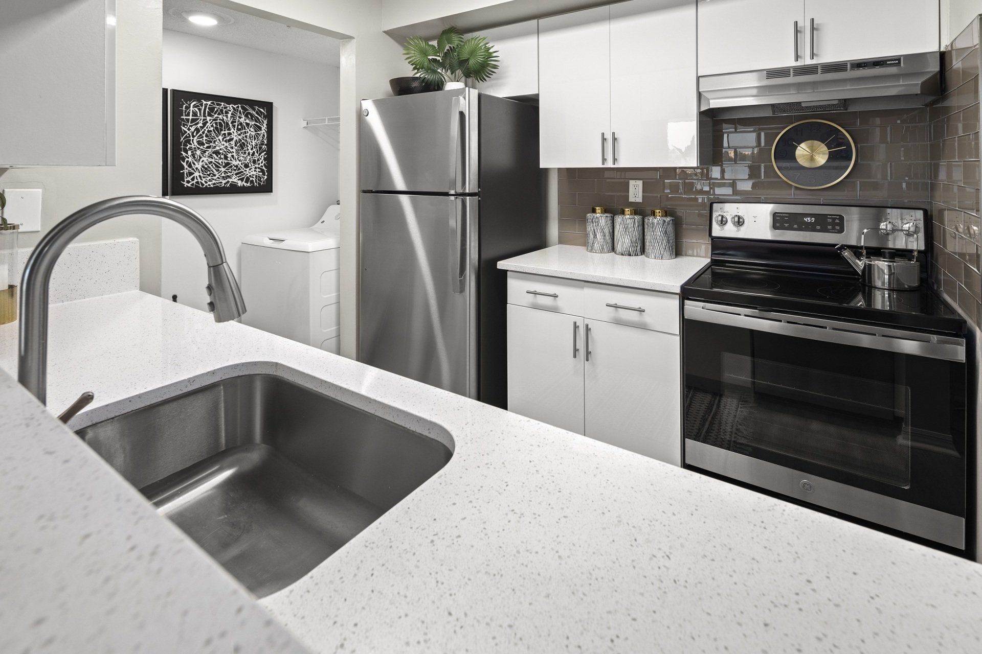 Modern kitchen with stainless steel appliances, white cabinets, and a quartz countertop.