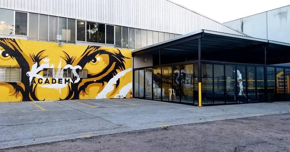 Academy building exterior with yellow mural, glass entrance, and metal awning