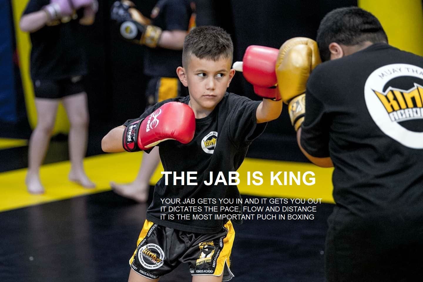 A young boy wearing boxing gloves is standing next to a man wearing boxing gloves.