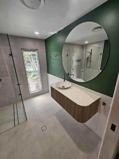 A bathroom with a sink and a round mirror.