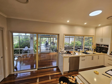 A kitchen with a lot of windows and a wooden floor.