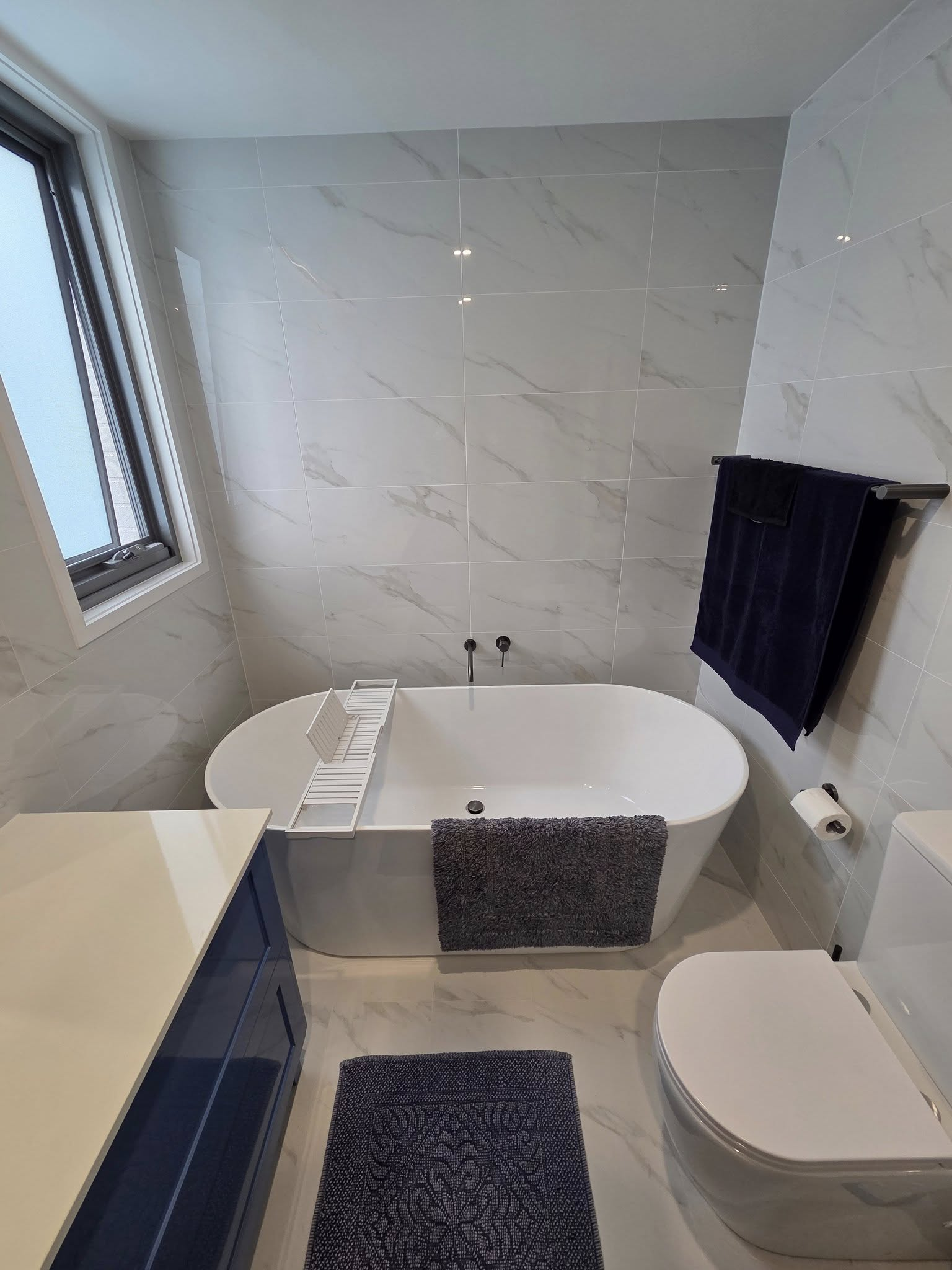 A bathroom with a bathtub , toilet , sink and window.