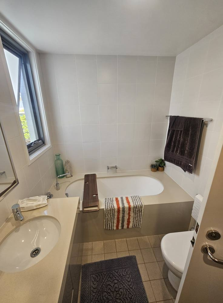 A bathroom with a tub , sink , toilet and window.