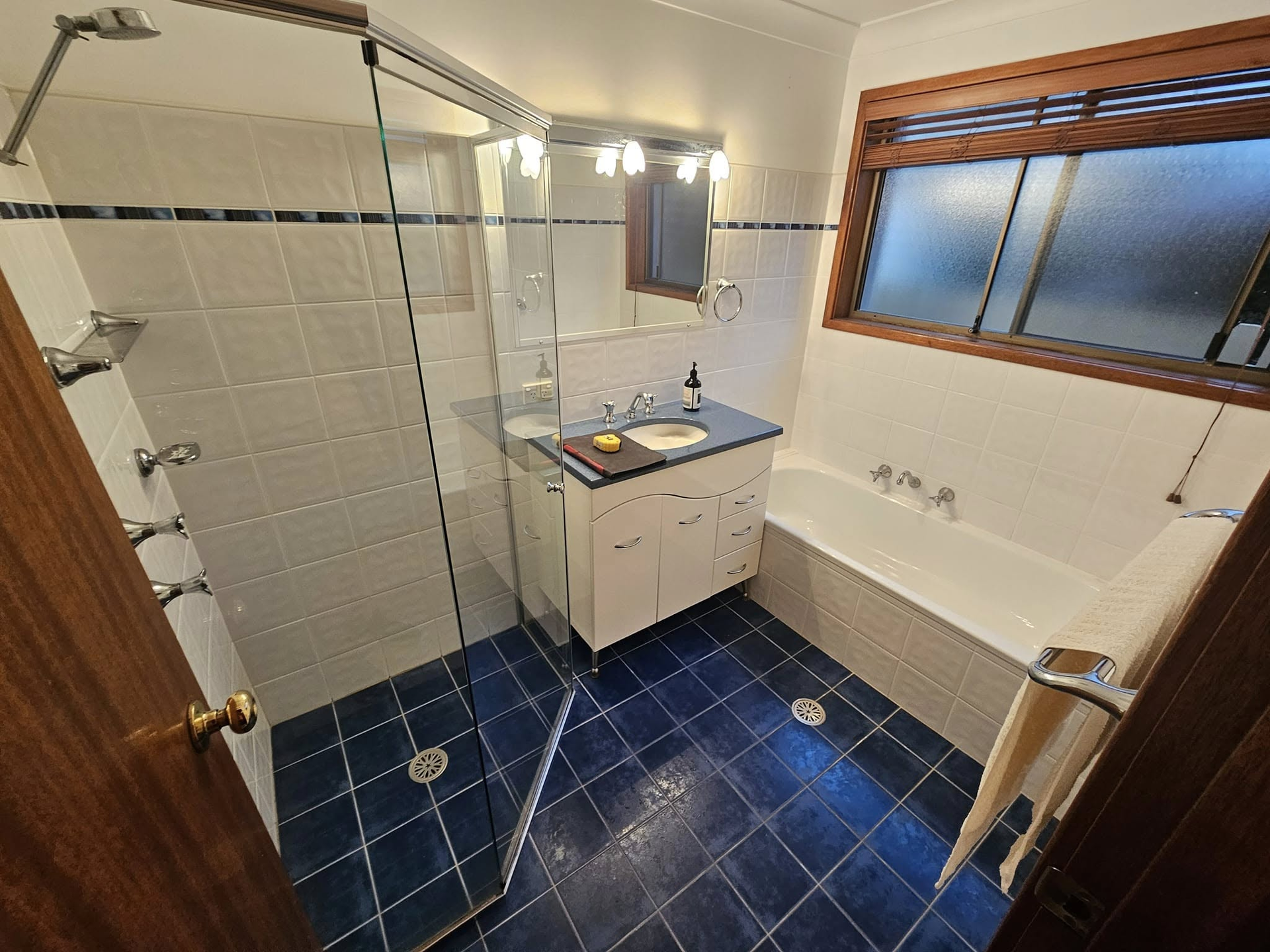 A bathroom with a sink , bathtub , shower and window.