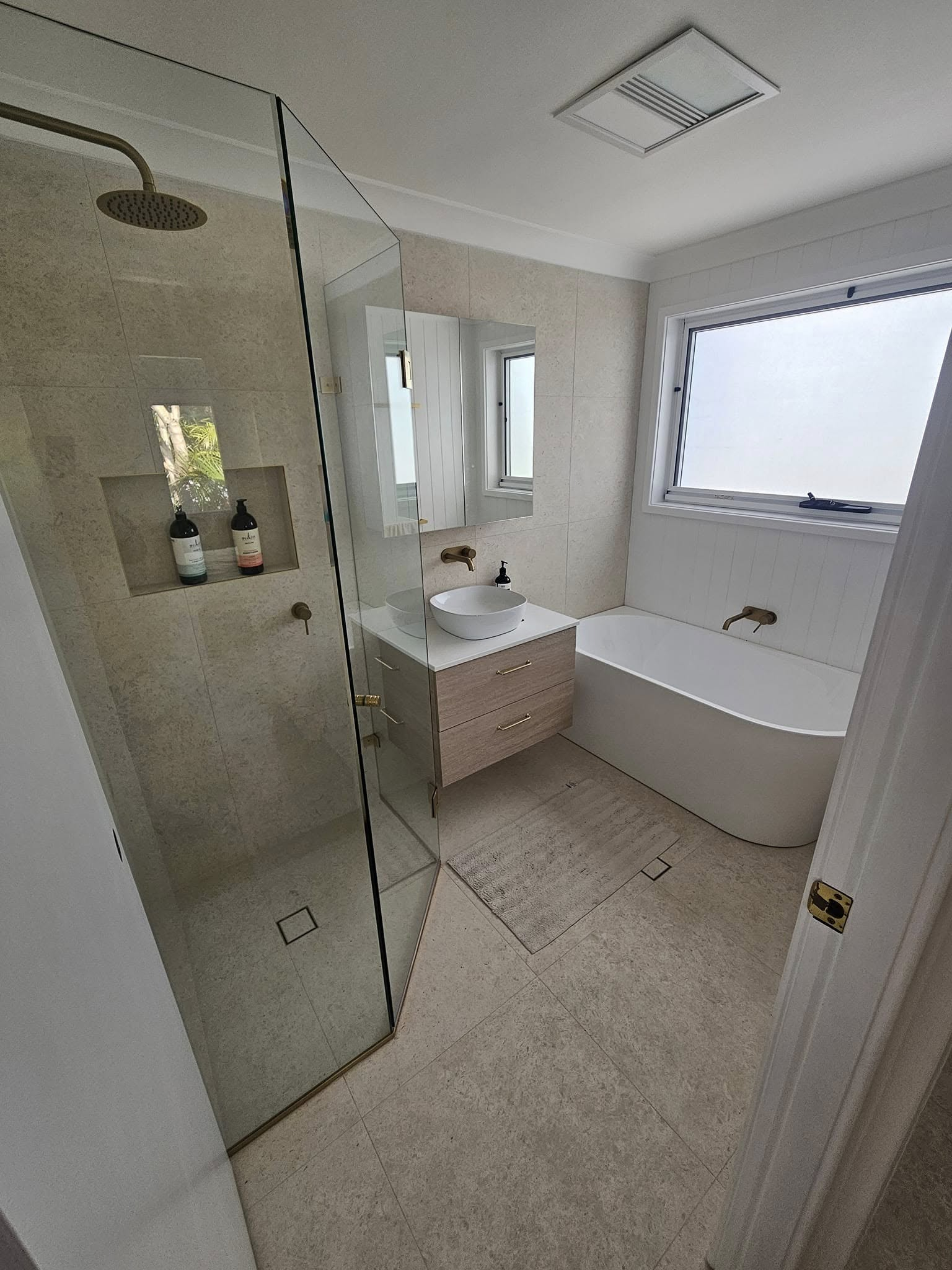 A bathroom with a tub , sink , shower and mirror.