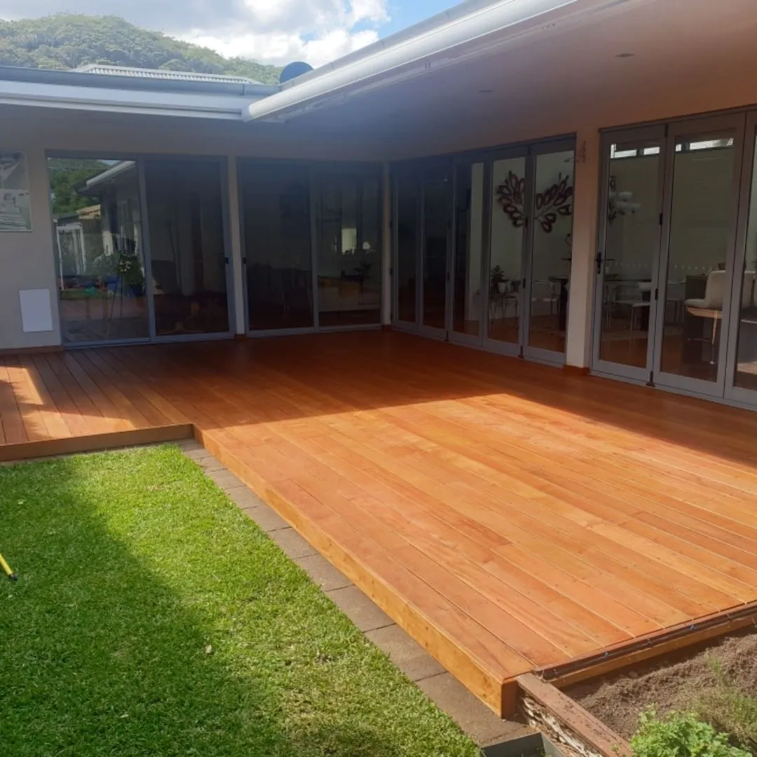 There is a large wooden deck in the backyard of a house.