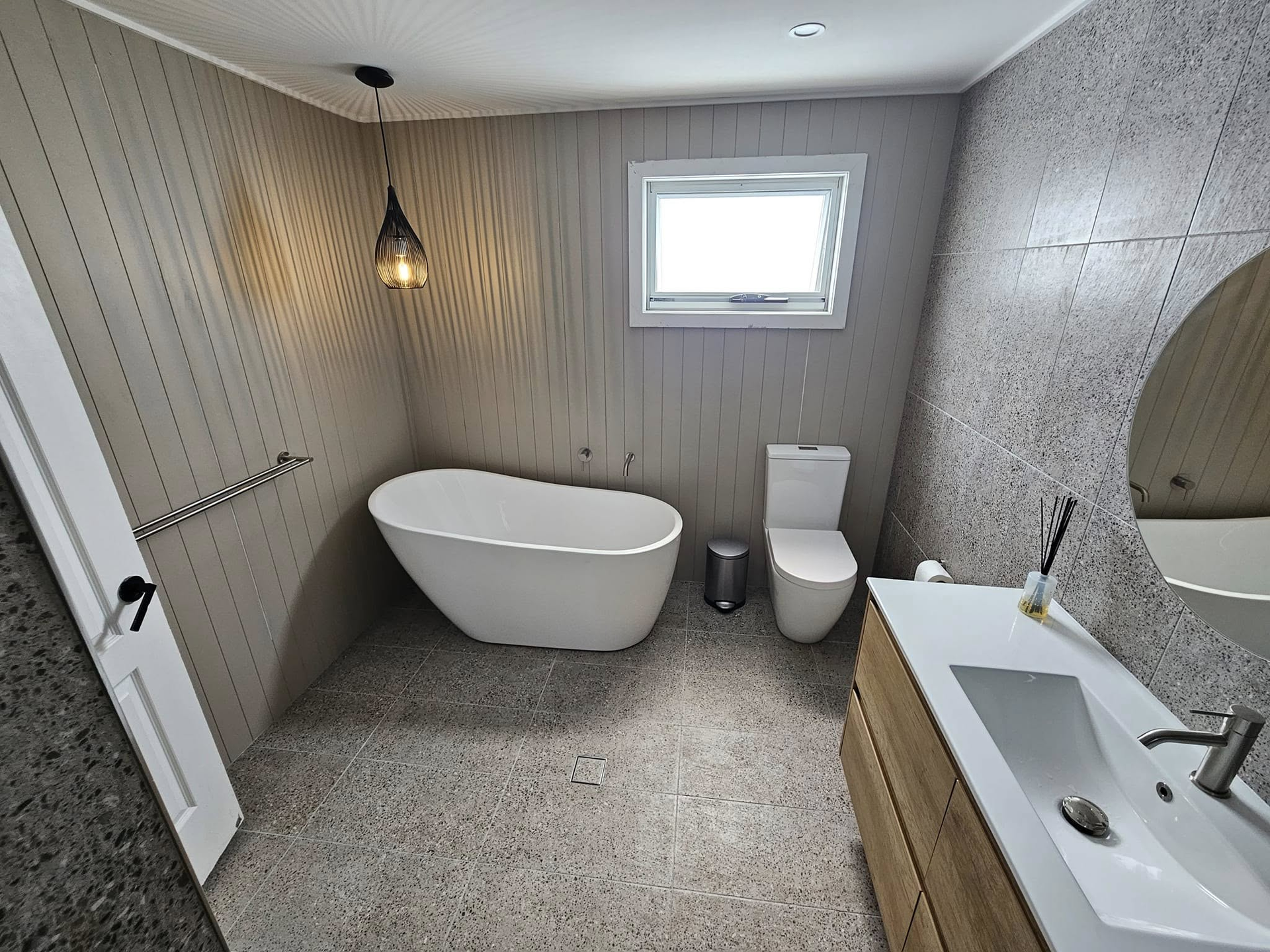A bathroom with a tub , toilet , sink and mirror.