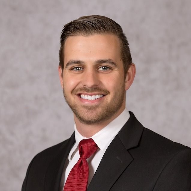 A man in a suit and tie is smiling for the camera