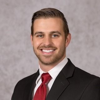 A man in a suit and tie is smiling for the camera.