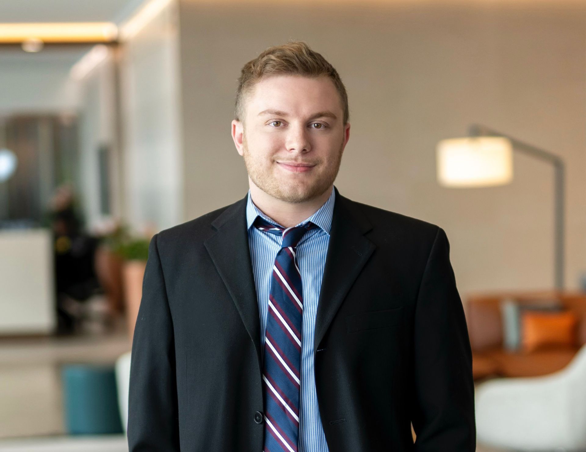 A man in a suit and tie is sitting in front of a bush.