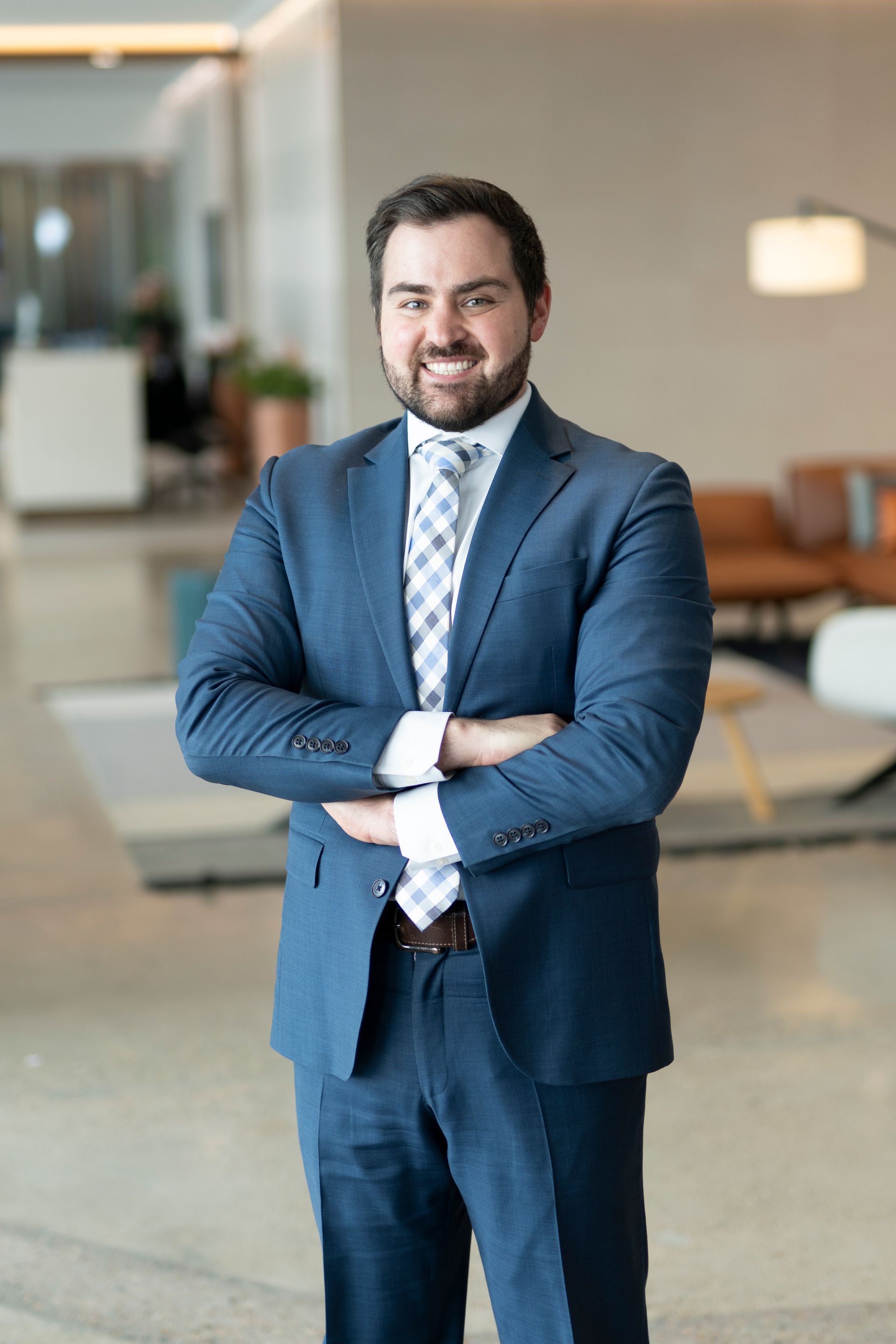 A man in a suit and tie is standing with his arms crossed.