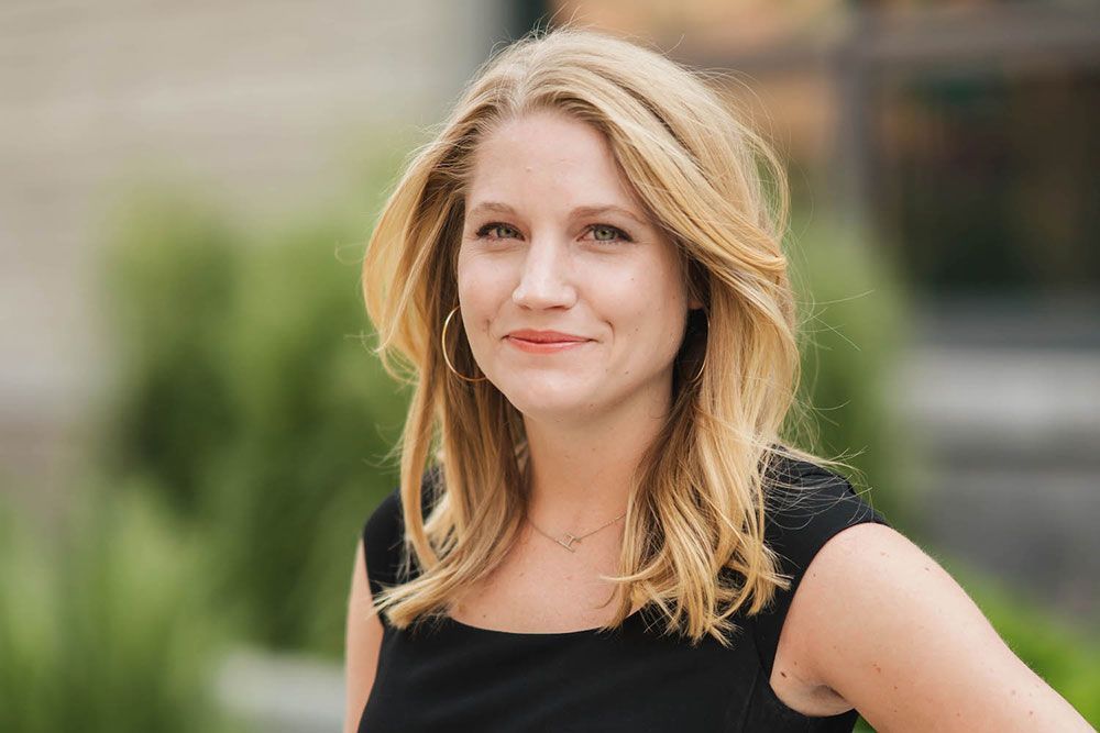 A woman in a black dress is smiling and looking at the camera.