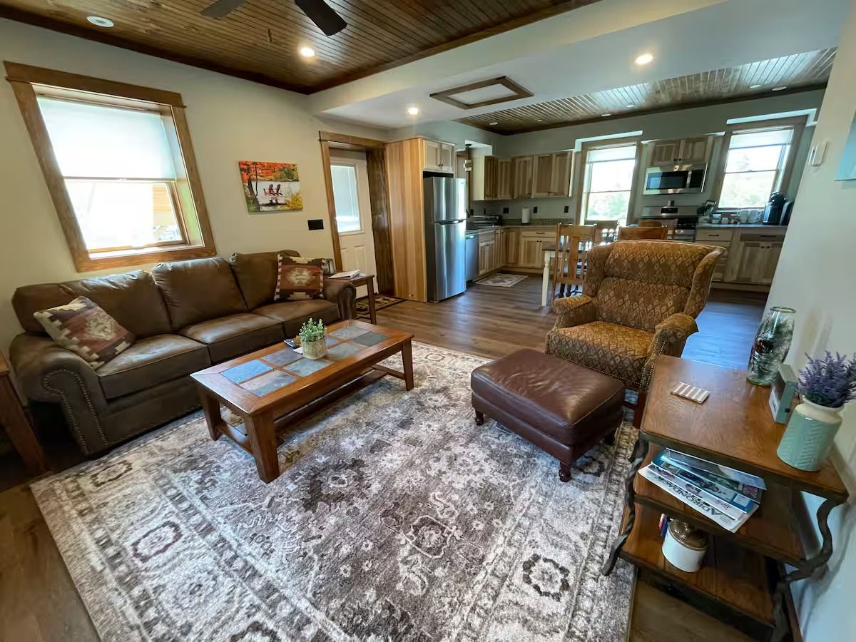 A living room with a couch , chair , coffee table and rug.